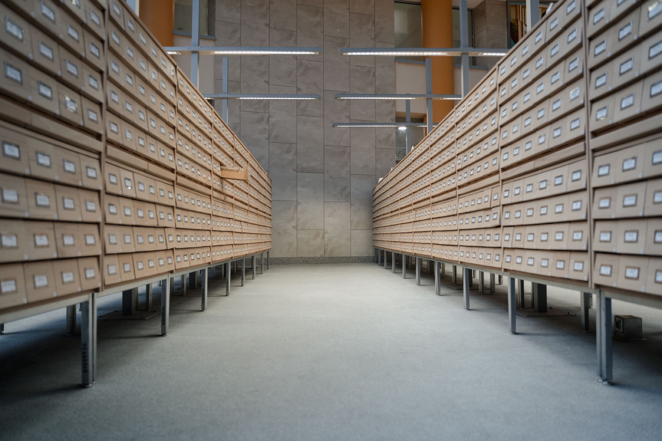 Rows of labeled archive drawers receding down a long aisle